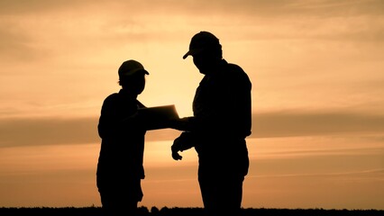 Fototapeta na wymiar silhouette two farmers work tablet, farming, teamwork group people, contract handshake agreement, golden silhouette people inspecting farm holding contract agronomists showing sign silhouettes concept