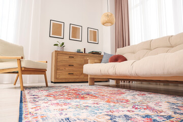 Beautiful rug, sofa, armchair and chest of drawers indoors, low angle view