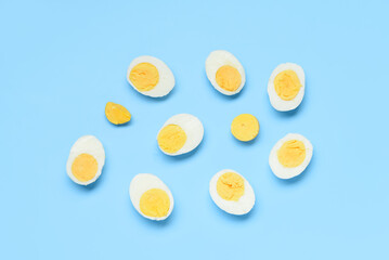 Halves of tasty boiled eggs on blue background