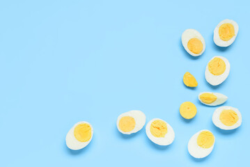 Halves of tasty boiled eggs with slice on blue background