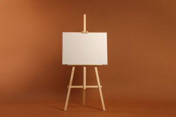 Wooden easel with blank canvas on brown background