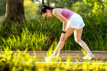 Asian  woman accident falling down on floor in the park while running exercise with knee pain