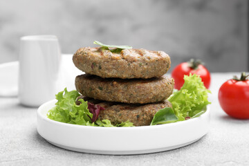 Delicious grilled vegan cutlets with lettuce on light grey table