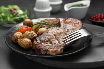 Tasty beef tongue pieces, rosemary and potatoes on grey table, closeup