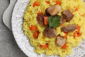 Delicious pilaf with meat on light grey table, closeup
