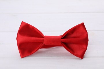 Stylish red bow tie on white wooden table