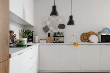 Interior of modern kitchen with white counters, sink, plate rack and utensils