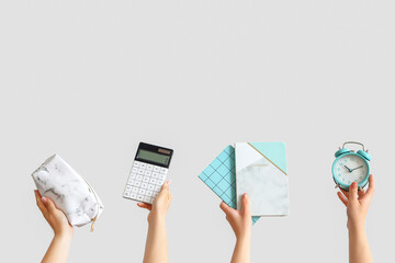 Female hands holding school supplies on grey background