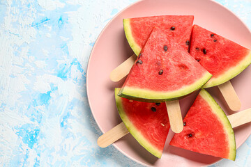 Plate with sweet watermelon sticks on light blue background