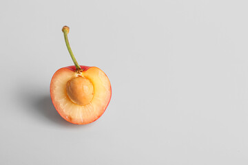 Half of sweet yellow cherry on grey background