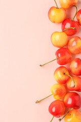 Many sweet yellow cherries on pink background