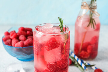 Glass and bottle of fresh raspberry lemonade with rosemary on white table