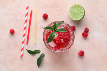 Glass of fresh raspberry lemonade with mint and lime on pink background
