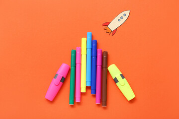 Markers with paper rocket on red background