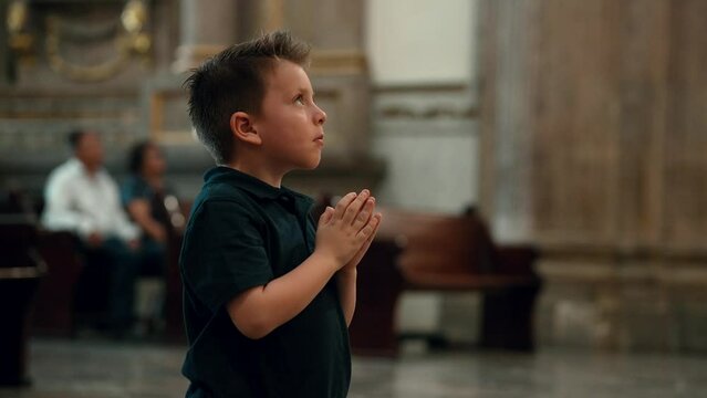 Ni&ntilde;o latino rubio hispano Rezando orando meditando con devoci&oacute;n hincado de rodillas en basilica de zapopan templo cristiano cat&oacute;lico santuario parroquia iglesia