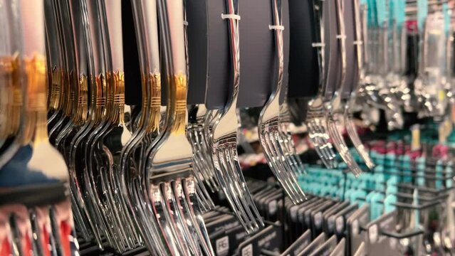 New cutlery - shiny forks hanging on the counter in the crockery store or tableware shop. Close-up