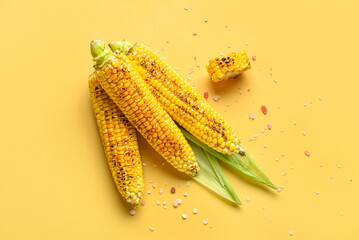 Tasty grilled corn cobs on yellow background