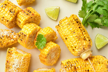 Cut tasty grilled corn cobs and parsley on light background