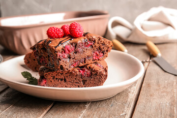 Plate with pieces of raspberry chocolate brownie on wooden table