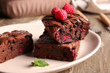 Plate with pieces of raspberry chocolate brownie on wooden table