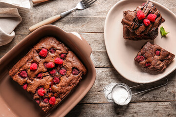 Baking dish and plate with raspberry chocolate brownie on wooden table