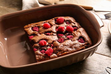Baking dish with raspberry chocolate brownie on wooden table