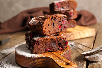 Board with pieces of raspberry chocolate brownie on wooden table