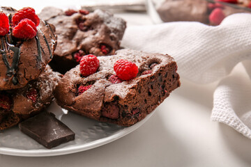 Plate with pieces of raspberry chocolate brownie on white background