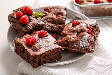 Plate with pieces of raspberry chocolate brownie on white background