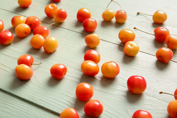 Many sweet yellow cherries on green wooden background