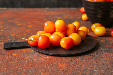 Board with sweet yellow cherries on dark background