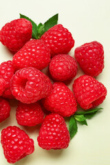 Heap of fresh raspberries and mint on light background