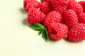 Heap of fresh raspberries and mint on light background