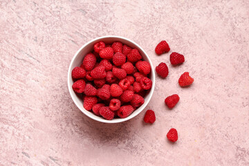 Bowl with fresh raspberries on pink background