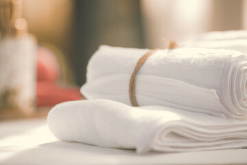 SPA concept: roll of white fluffy bath towels with gblurred background