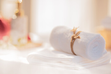 SPA concept: roll of white fluffy bath towels with blurred background