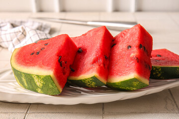 Plate with pieces of fresh watermelon on white tile table