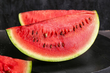 Fototapeta na wymiar Board with pieces of fresh watermelon on black background