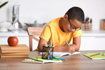 Little African-American boy doing homework in kitchen