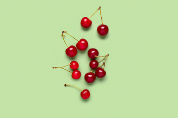 Naklejka na ściany i meble Red sweet cherries on green background