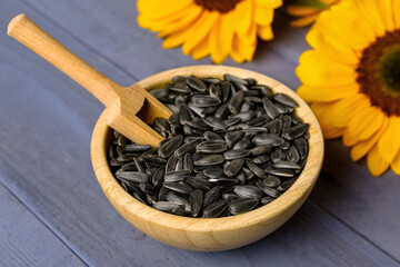 Bowl with sunflower seeds on purple wooden background