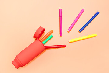 Different colorful markers in case on orange background