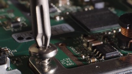 Closeup shot of unscrewing a screw from a hard drive. Different small components. Microchip. Storage. Fixing computer technology. Screwdriver. Selective focus.