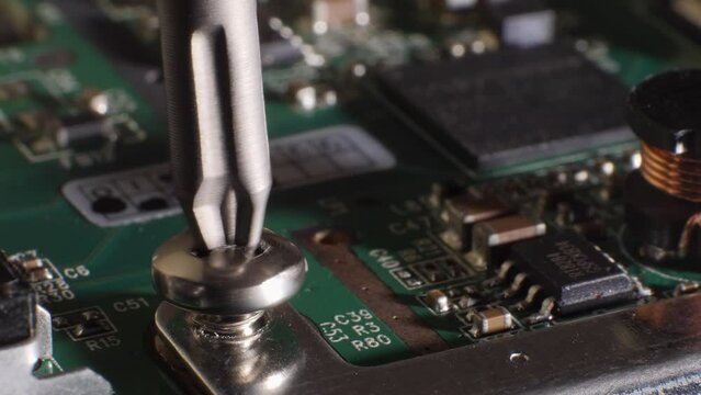 Closeup shot of unscrewing a screw from a hard drive. Different small components. Microchip. Storage. Fixing computer technology. Screwdriver. Selective focus.
