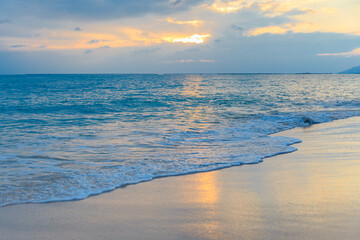 Sunset on the Sanya beach, the sun shines through the clouds on the golden sea and beach