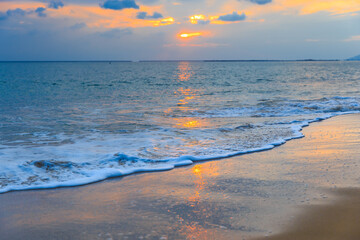 Sunset on the Sanya beach, the sun shines through the clouds on the golden sea and beach