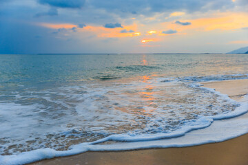 Sunset on the Sanya beach, the sun shines through the clouds on the golden sea and beach