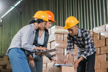 supervisor corrects the work of two factory employees during a visit to the factory warehouse