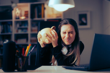 Stressed Businesswoman Shaking an Empty Piggy Bank for Money. Woman with online shopping addiction...