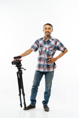 Fototapeta na wymiar a smiling cameraman in plaid shirt standing with one hand on his waist and the another hand holding the camera